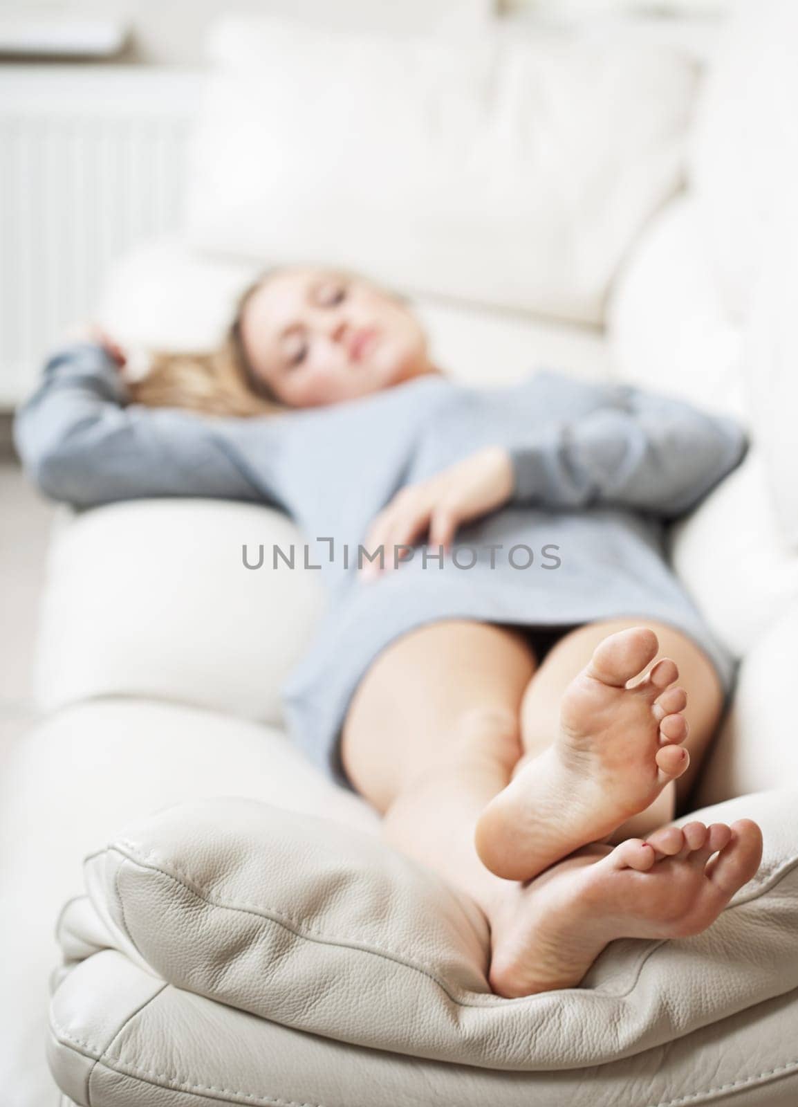 Barefoot young woman lying on sofa, shallow depth of field, focus on foot soles
