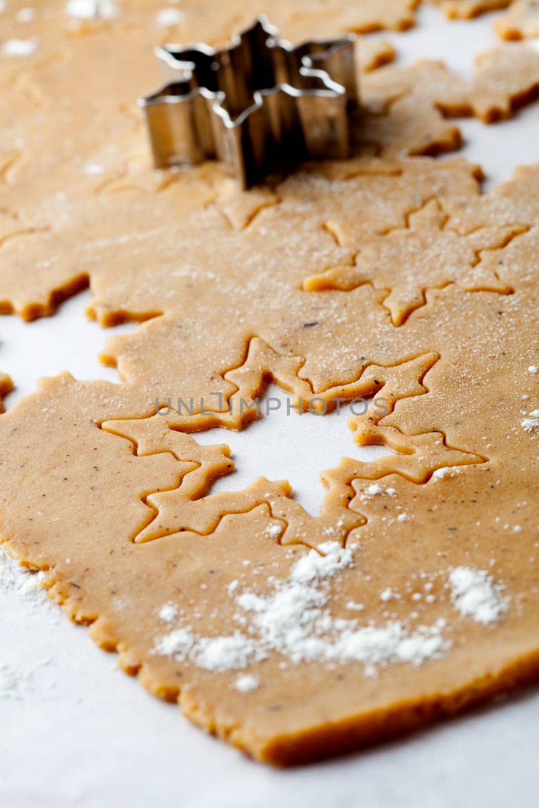 Making gingerbread cookies for Christmas. Gingerbread dough with star shapes and a cutter.