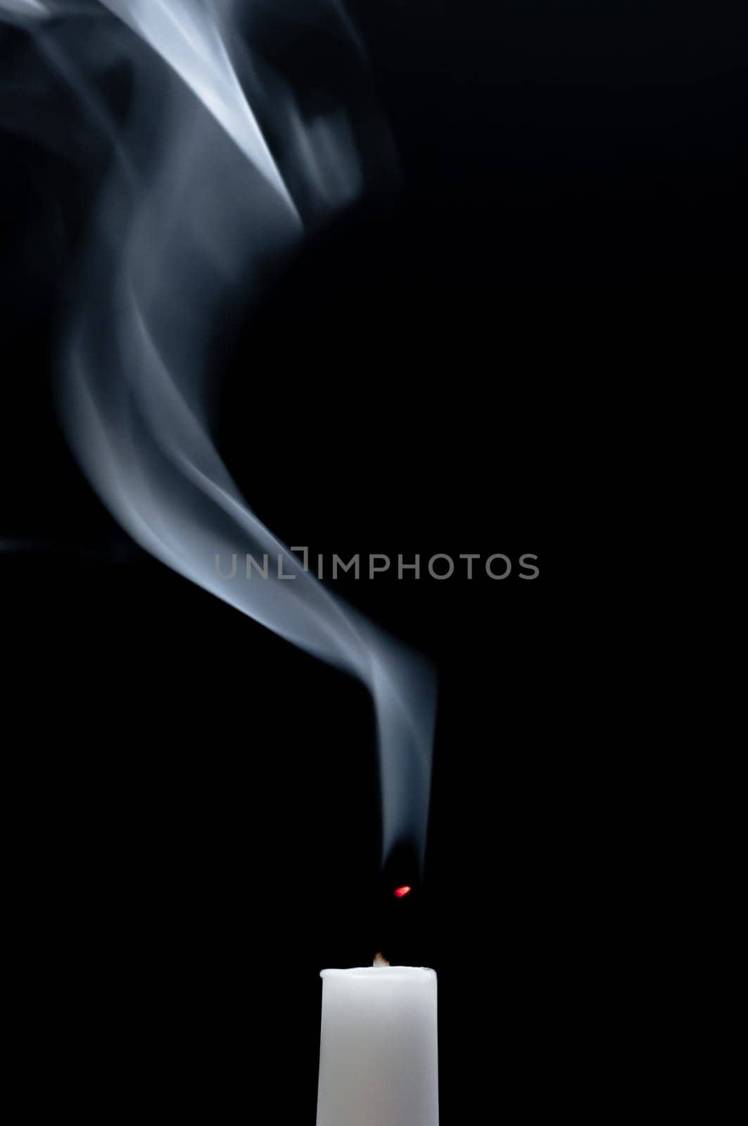 A white candle smokes after blowing out