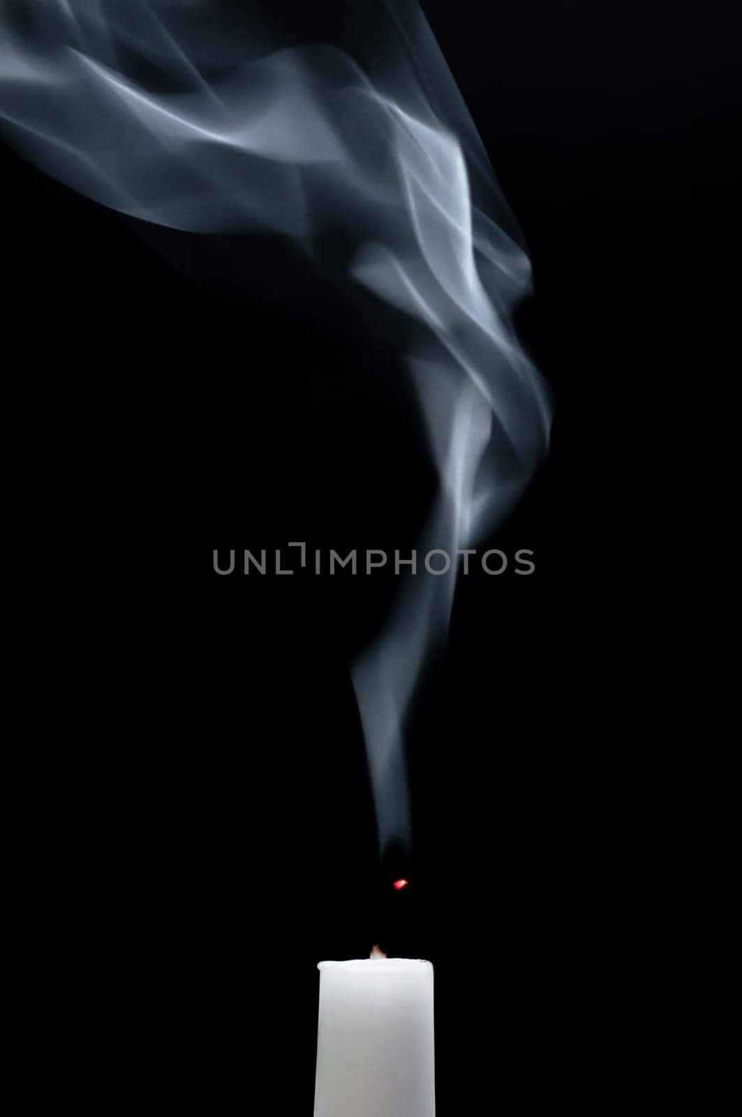 A smoking white candle with a smoldering wick