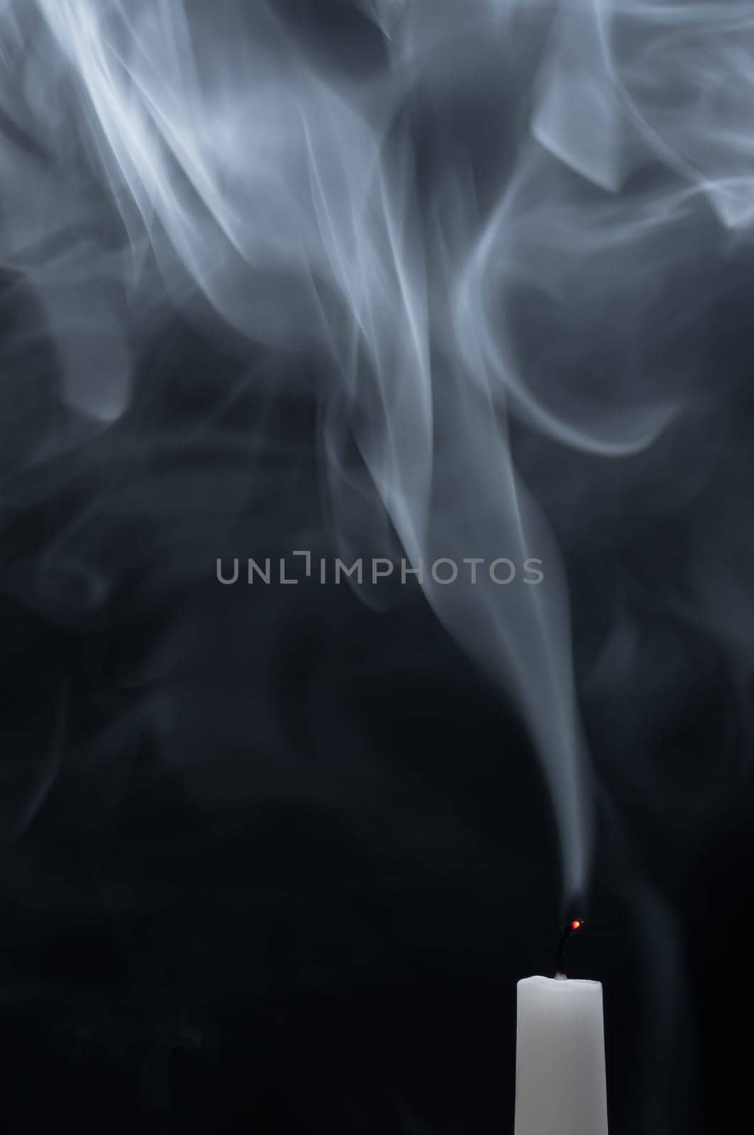 A white candle smokes after blowing out