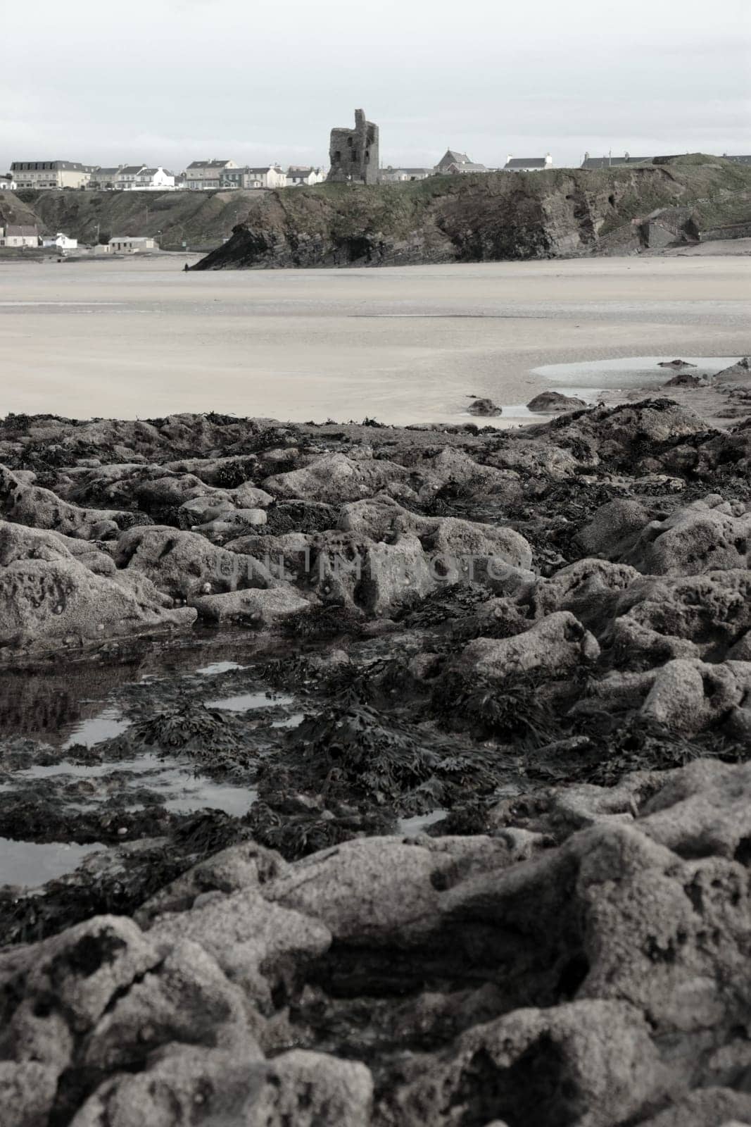 a rocky beach with castle on a warm day with a calm sea an ideal place to have a walk in ireland