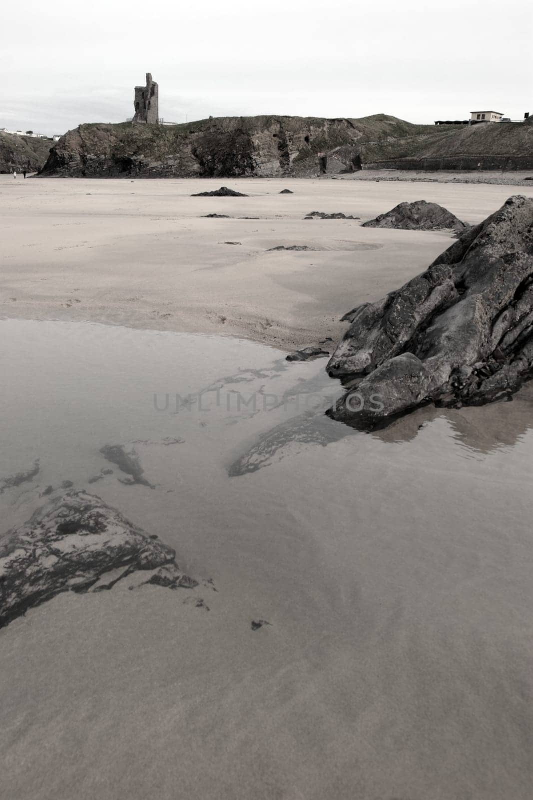 a rocky beach pool with castle on a warm day with a calm sea an ideal place to have a walk in ireland