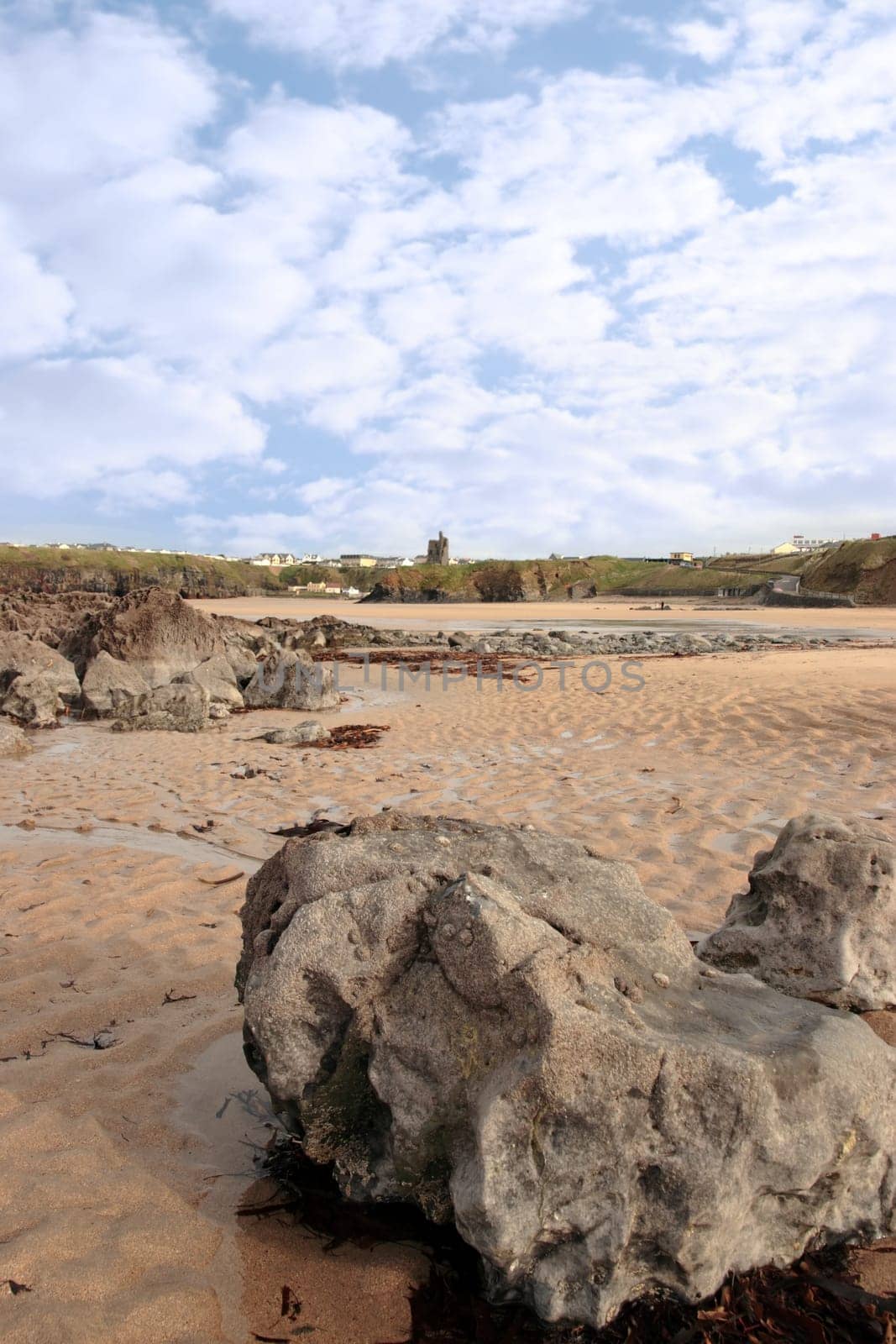 a rocky beach with castle on a warm day with a calm sea an ideal place to have a walk in ireland