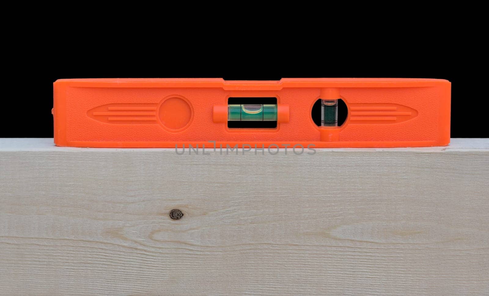 A red level on top of a wood 2X4 stud. The level indicates that the wood is level.