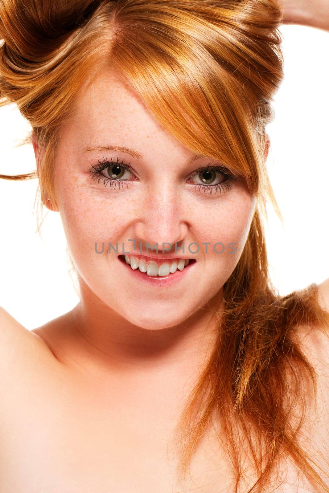 Young redhead woman lifting her hair on white background