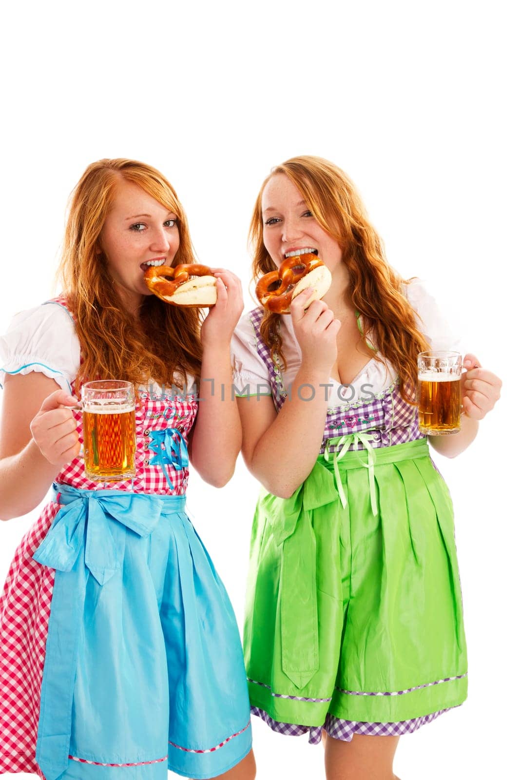 Two women in dirndl with beer eating pretzels on white background