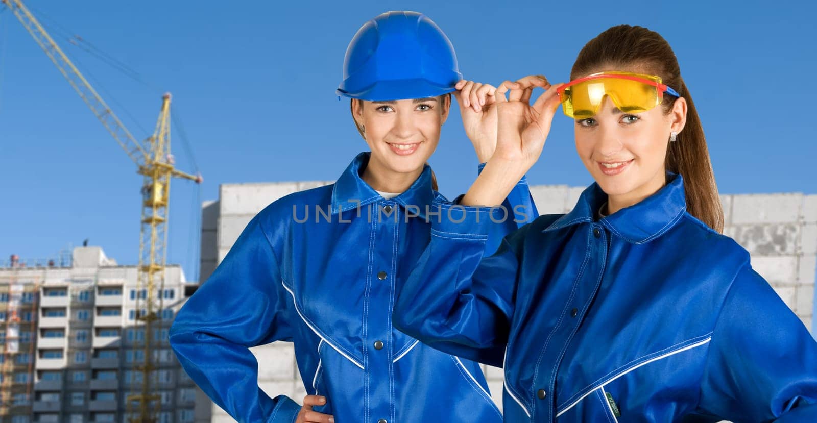Builder pretty girls at safety glasses on a building background