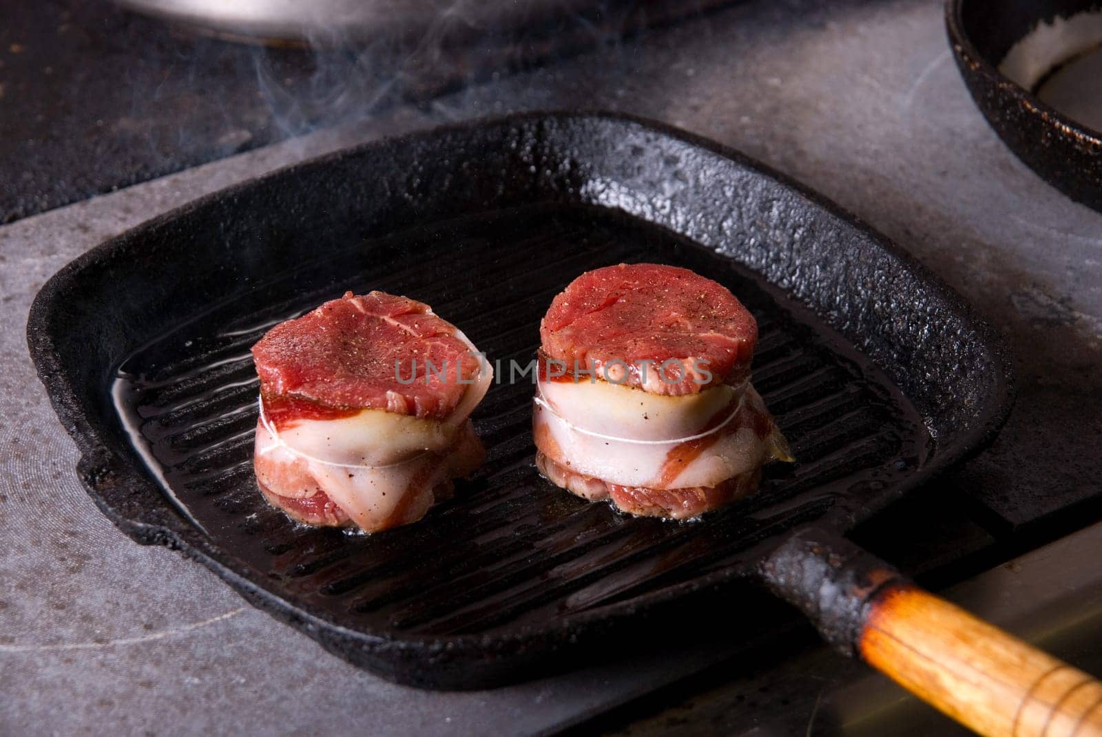 Tasty beef steak grilling in a cast-iron ribbed fry pan