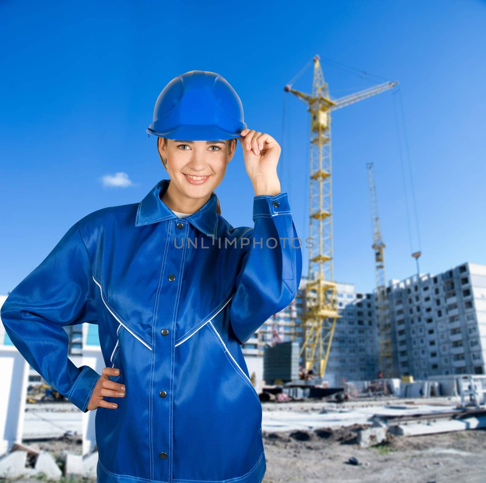 Builder pretty girl at helmet on a building background
