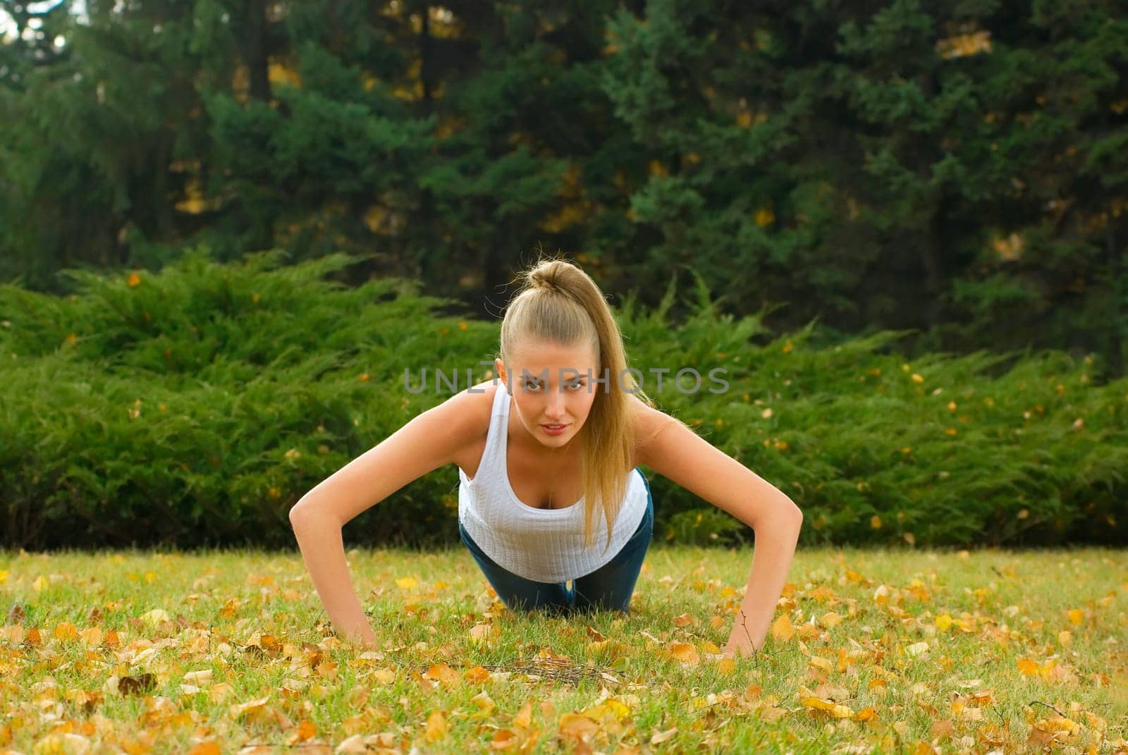 Beauty female doing push ups in the park