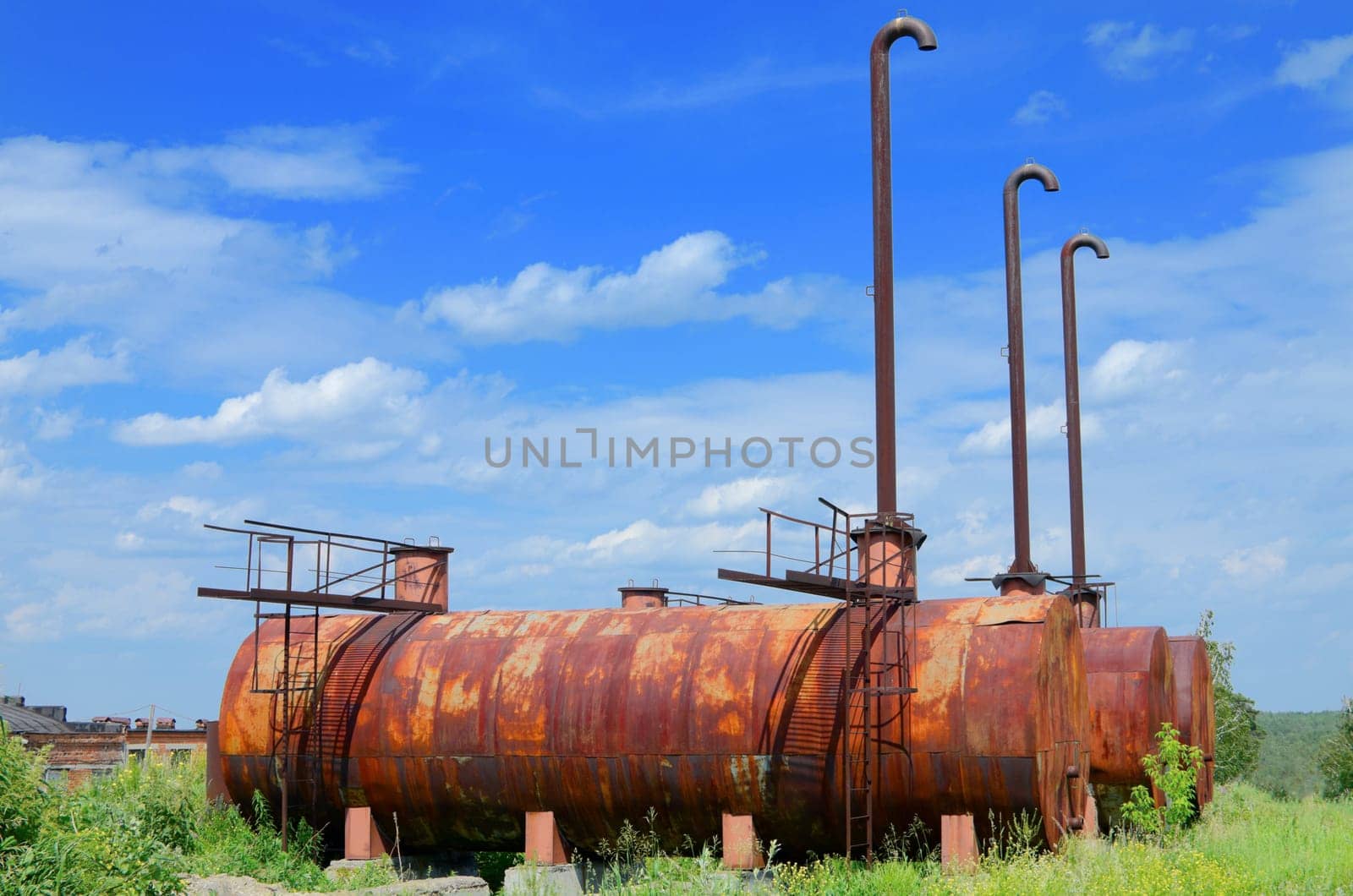 Old and rusty reservoirs surrounded by long green grass