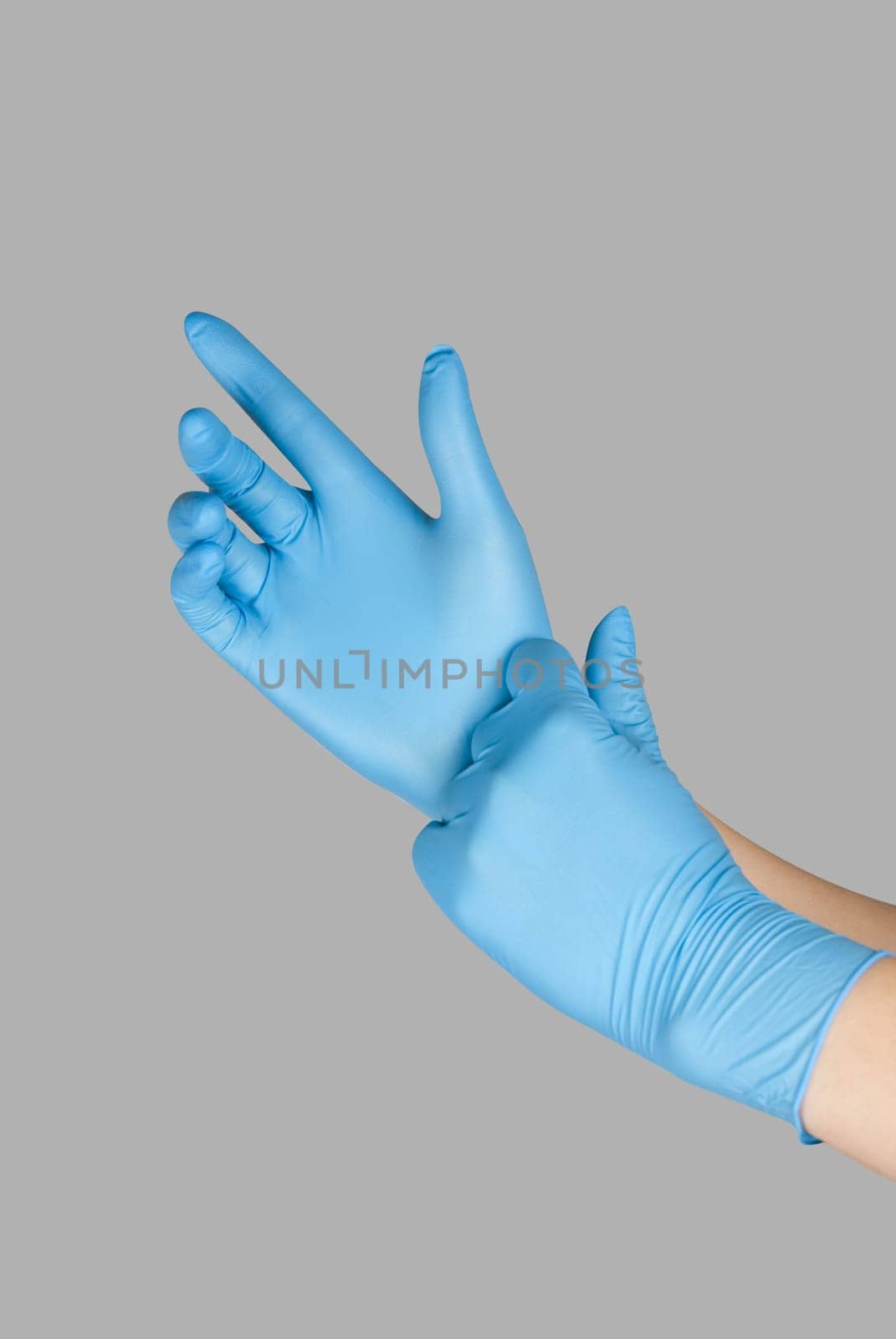 Blue gloves on a hand on a grey background