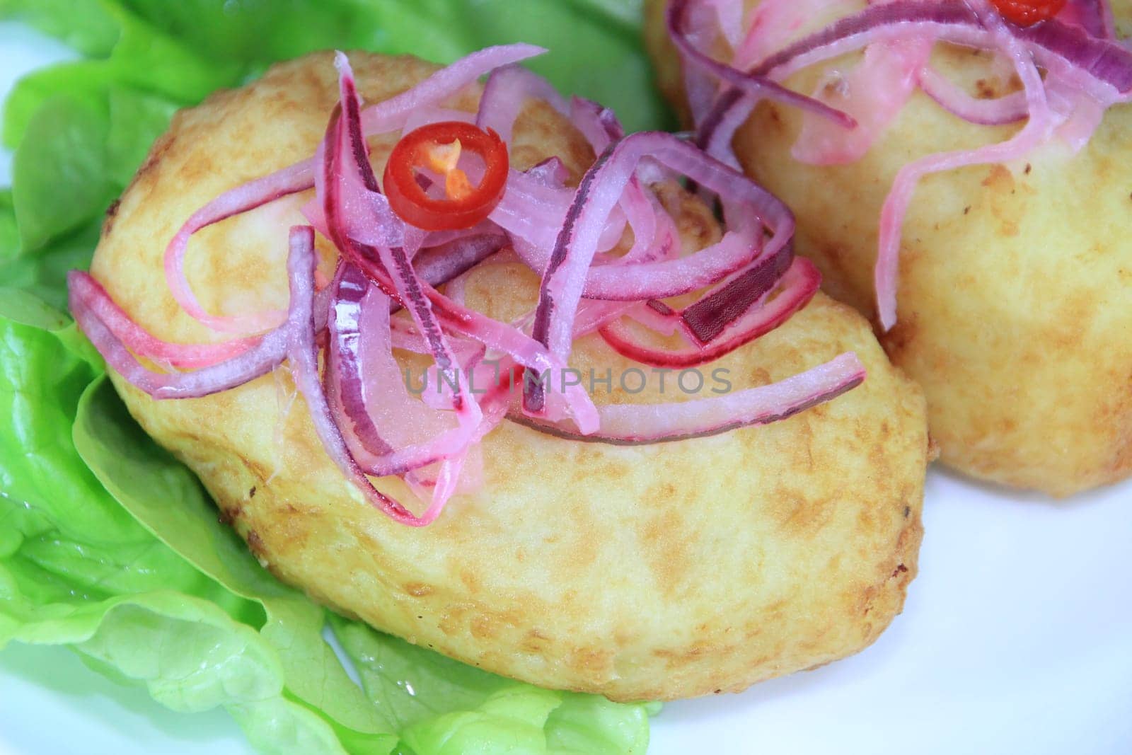 A close up of a papa rellena (a traditional Peruvian stuffed potato dish) on a pale blue plate.