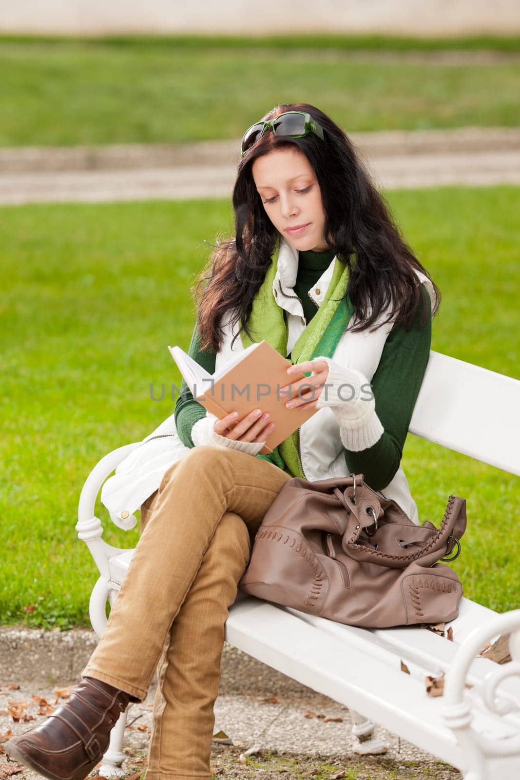 Autumn park young woman reading book sitting on the bench