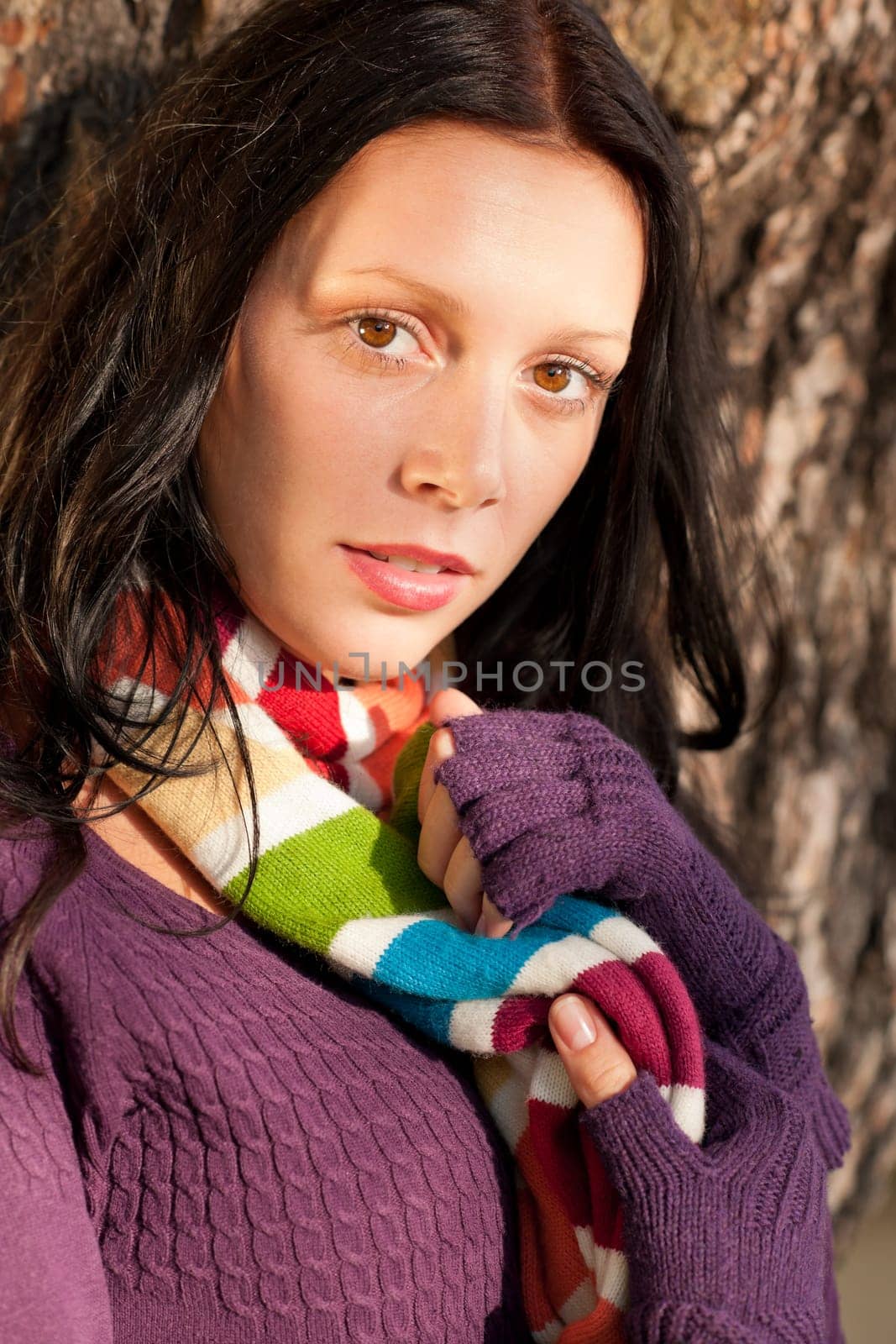 Winter outfit portrait of beautiful female model posing by tree bark