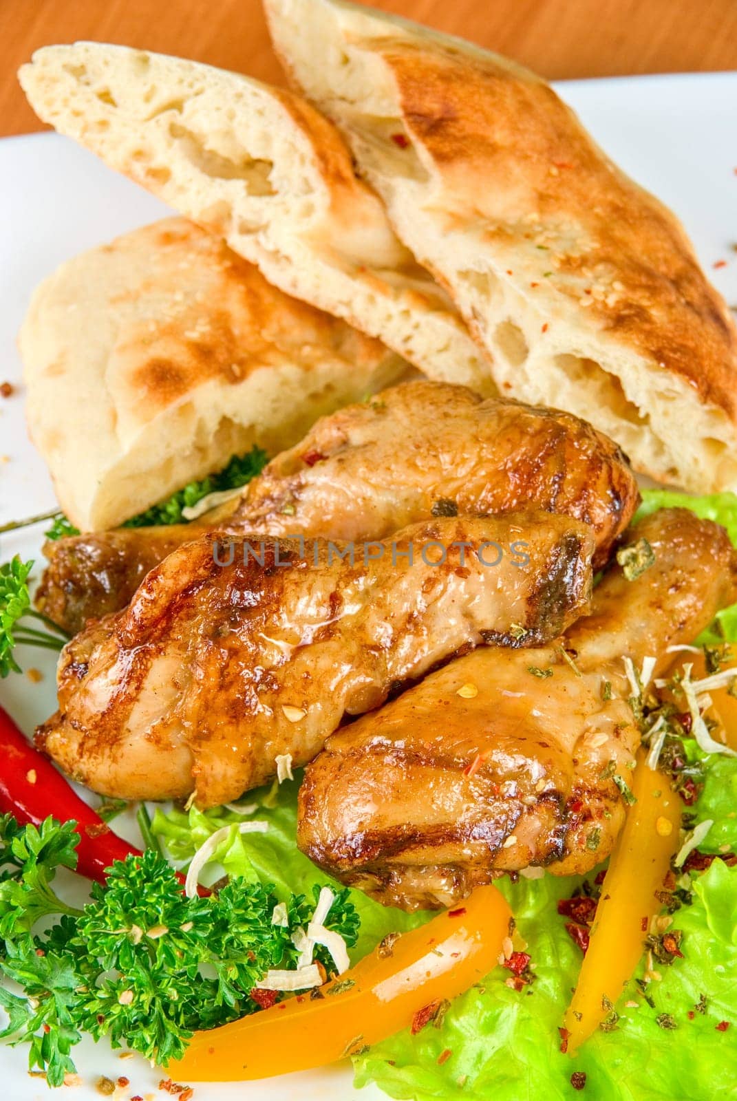 roasted chicken drumstick garnished with fresh green salad, pepper and greens