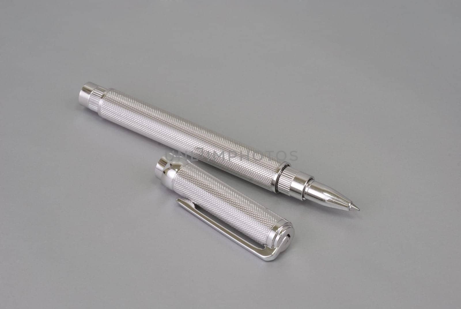 Stylish ballpoint pen of white gold on a grey