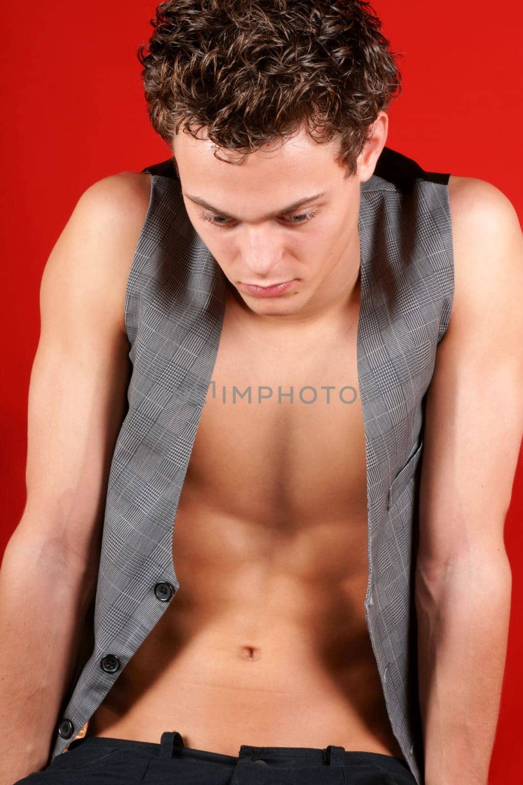 Portrait of a sad young man with waistcoat over a red background. Selective soft focus.