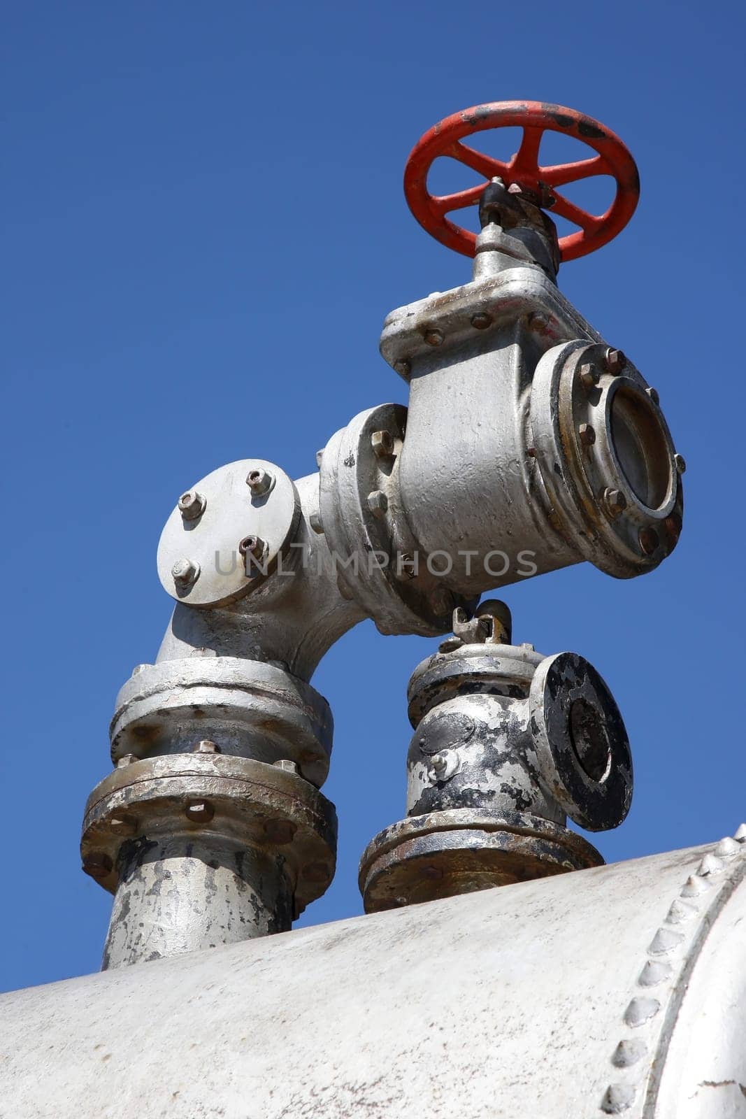 An old steam valve an d tap on a steel boiler