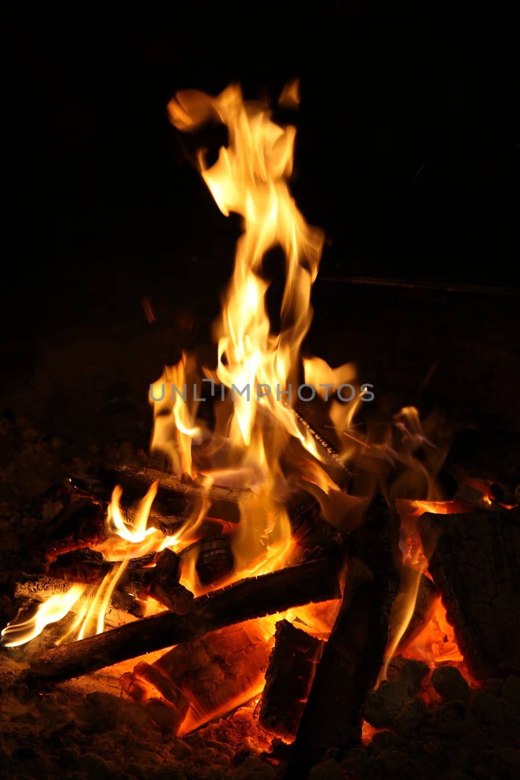 Hot flames and glowing embers of a camp fire