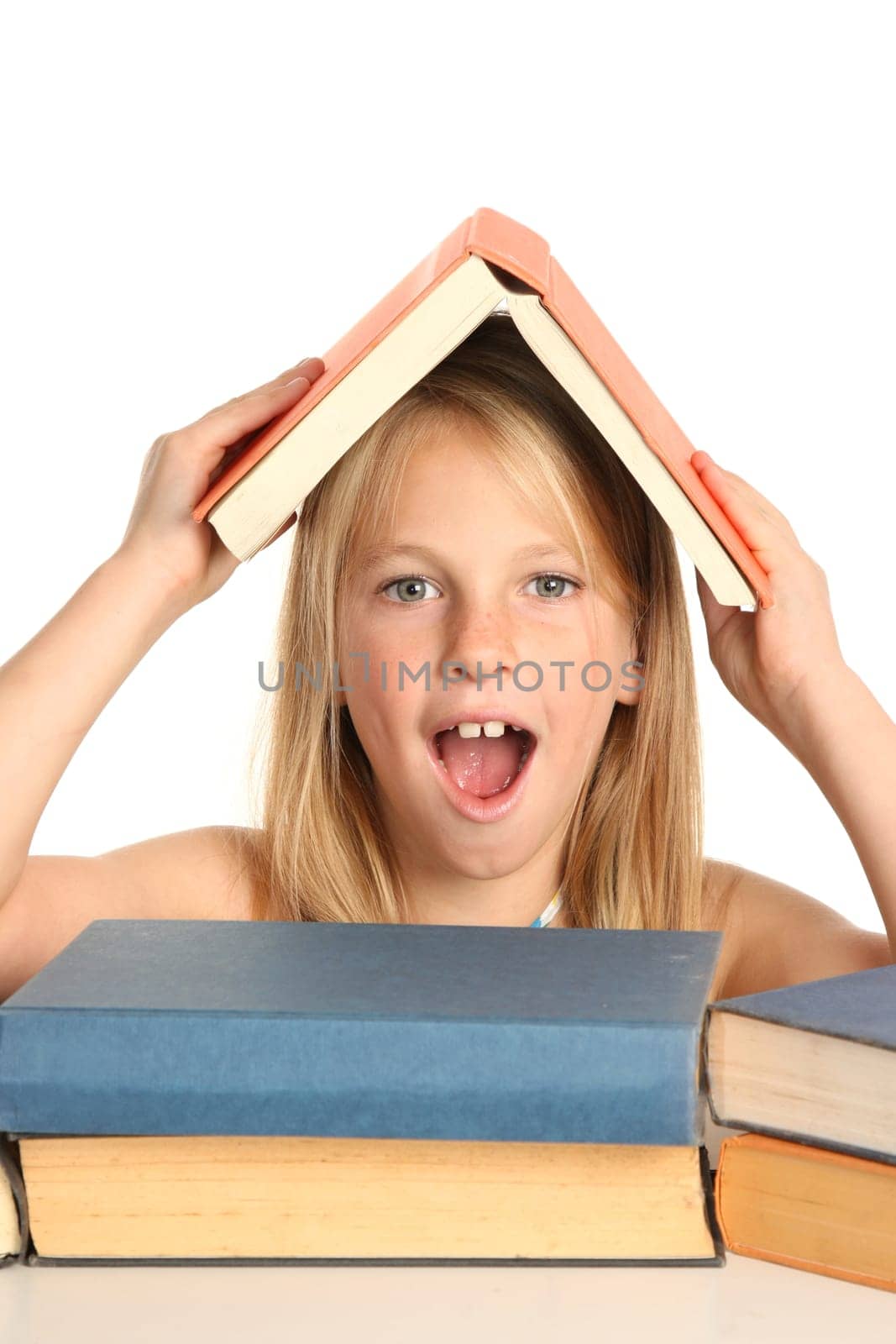 Lovely young school school with pile of books and one on her head