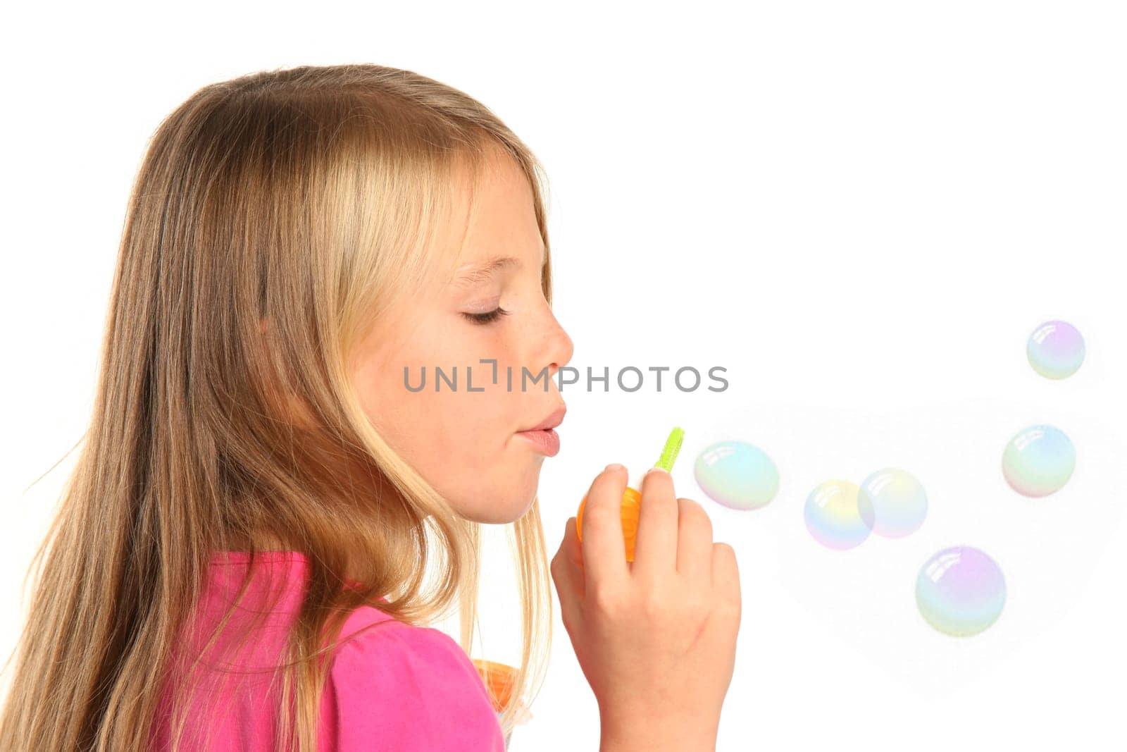 Little girl with blond hair blowing soap bubbles