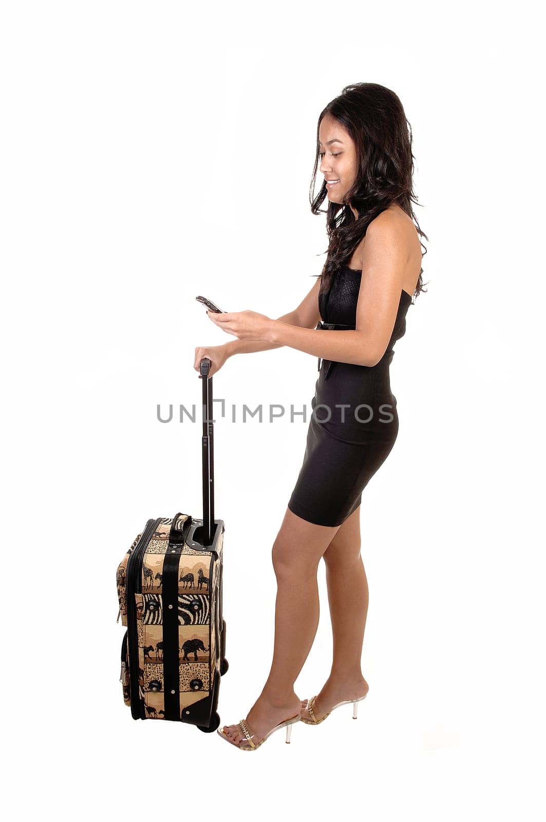 A very slim Asian woman with long brunette hair and a suitcase, with her cell phone in her hand smiling at the message, for white background.