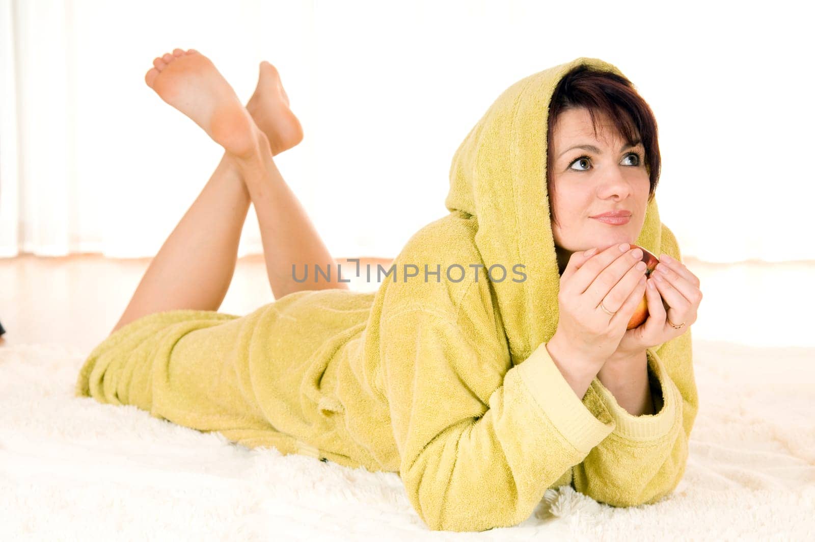 Woman in robe with  apple lying on the floor