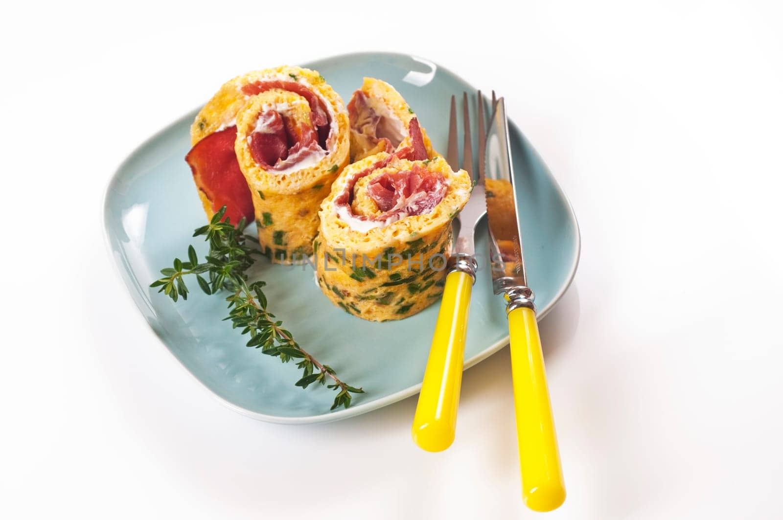 Omelette roll with ham and cream cheese on blue plate