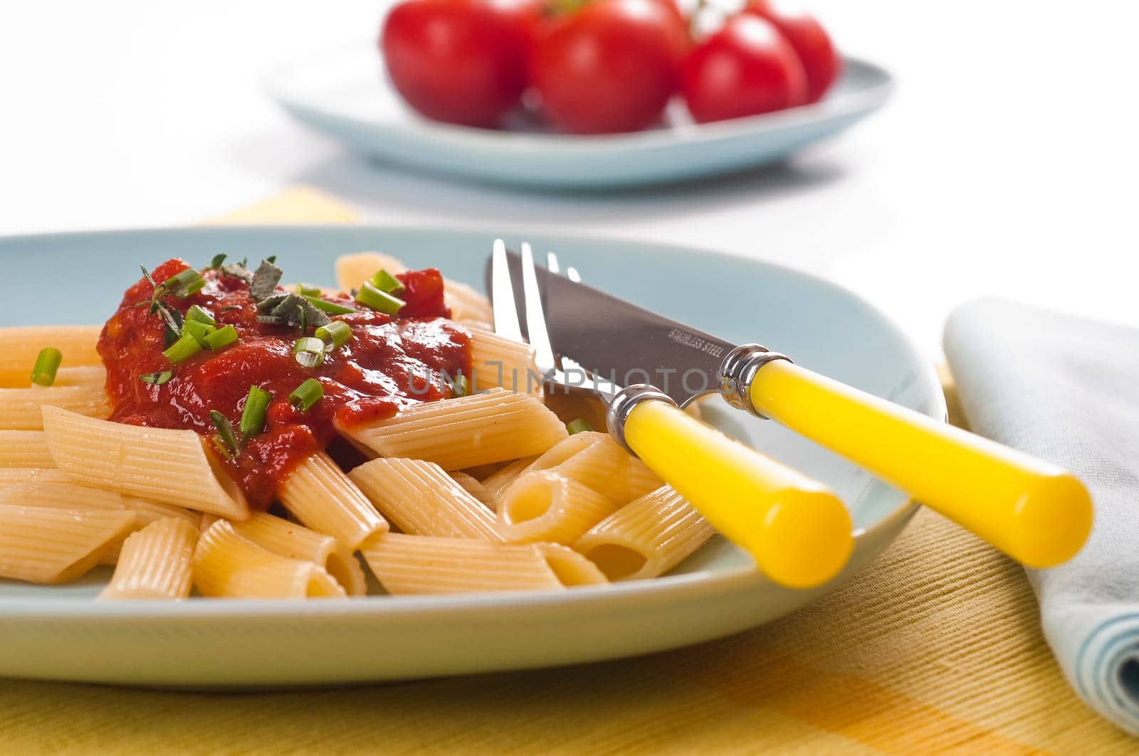 Pasta with tomato sauce and fresh chives on blue dishes