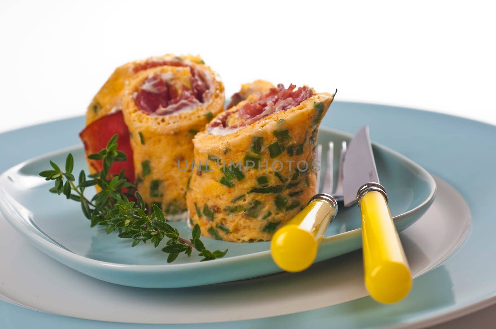 Omelette roll with ham and cream cheese on blue plate