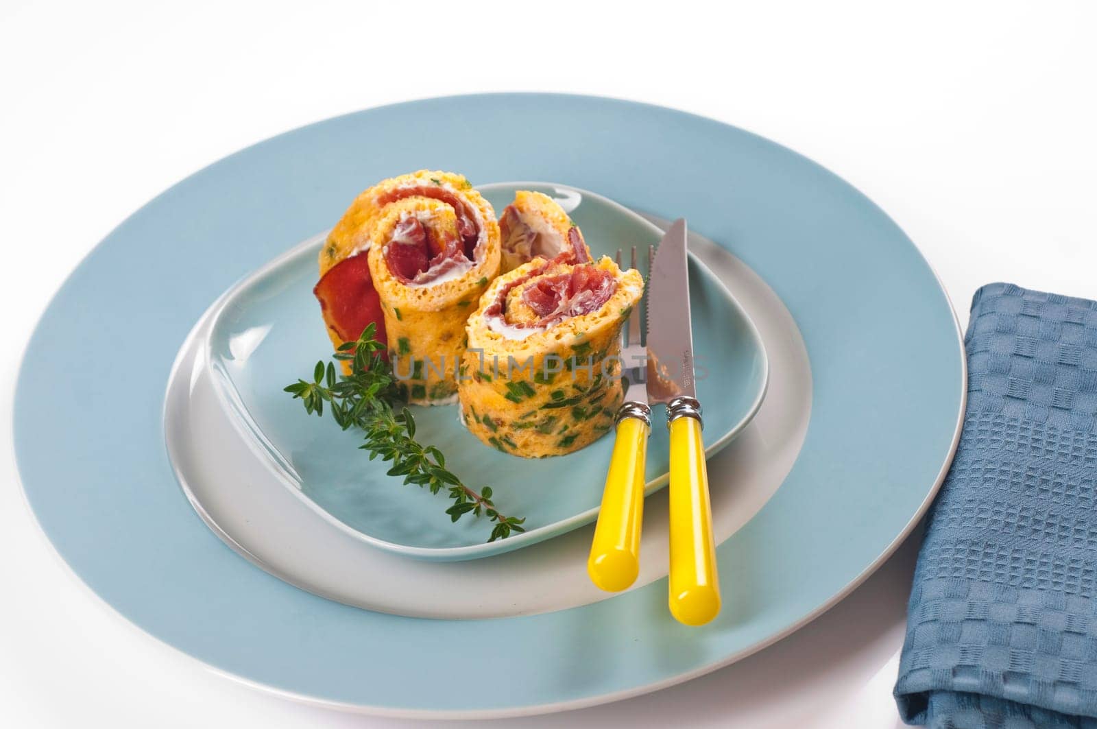 Omelette roll with ham and cream cheese on blue plate