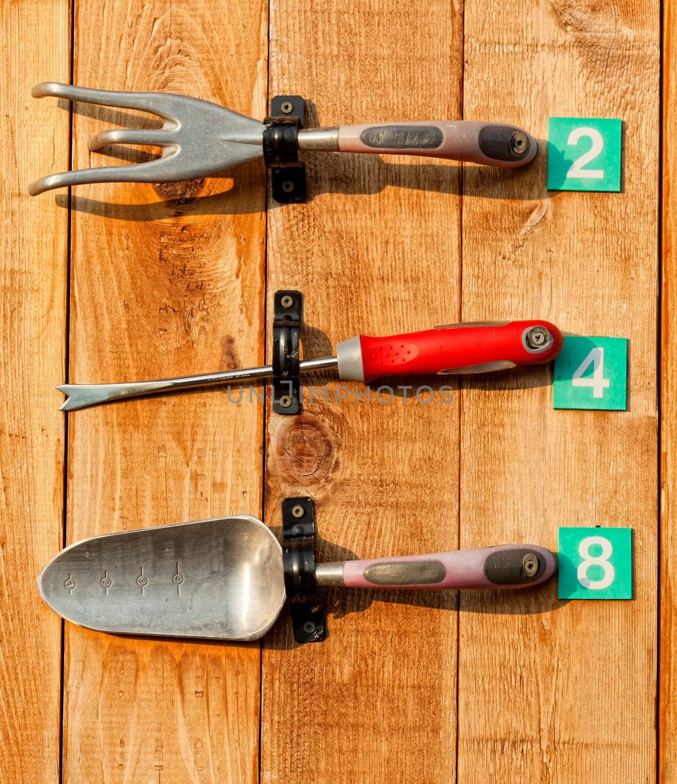 A set of garden tools on display fastened to a wooden board
