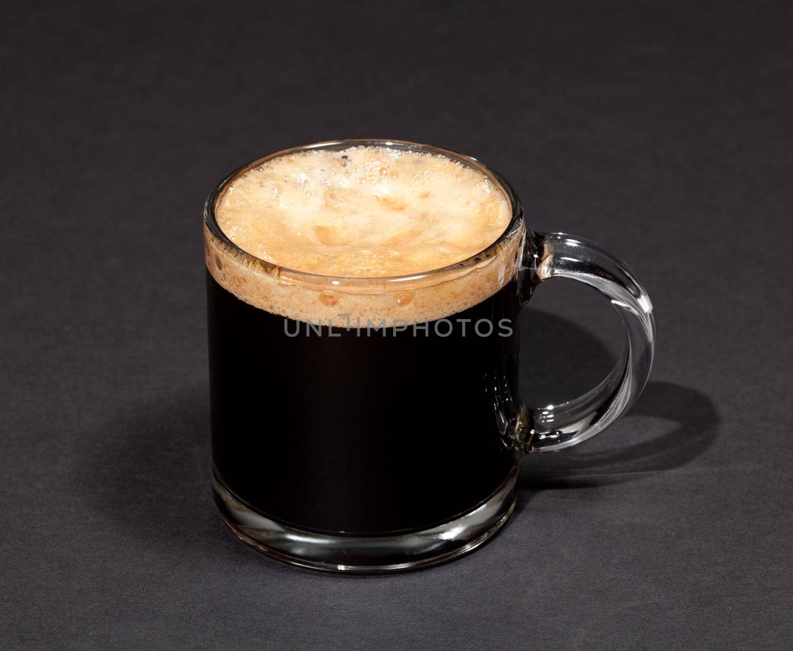 Black expresso coffee with heady froth in a glass mug or cup