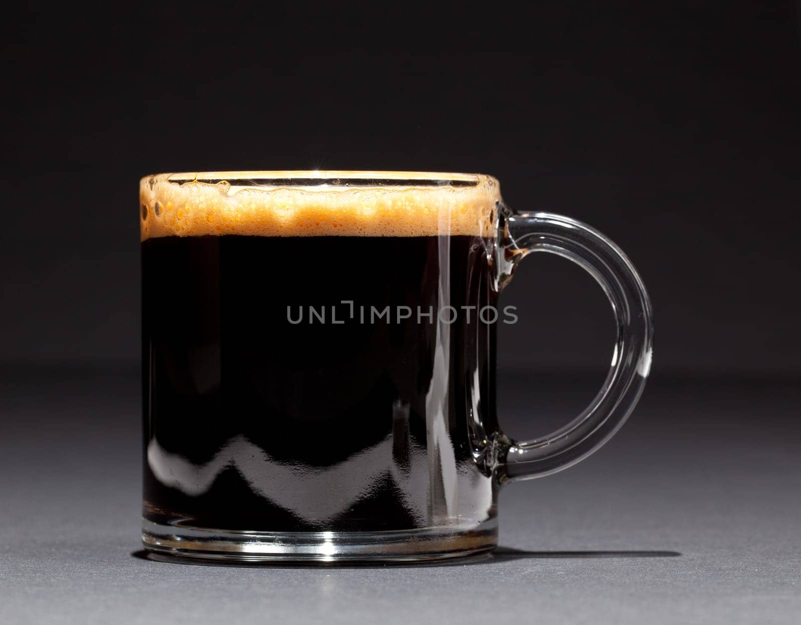 Black expresso coffee with heady froth in a glass mug or cup