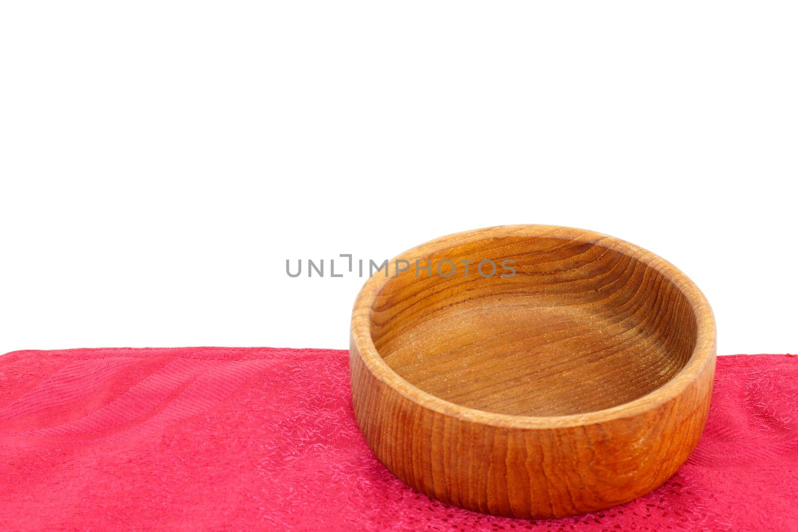 Empty teak wood bowl on a red placemat isolated naturally on a white background.