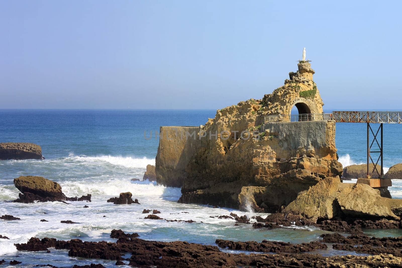panoramic views of the ocean with its rocks and waves over a blue sky