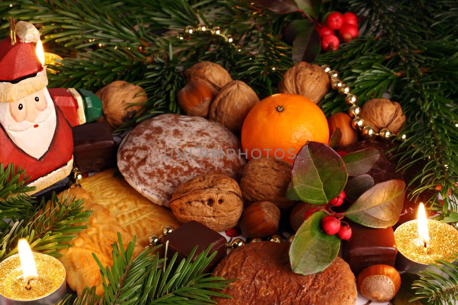 Sweets by candlelight with fir branches and decoration.