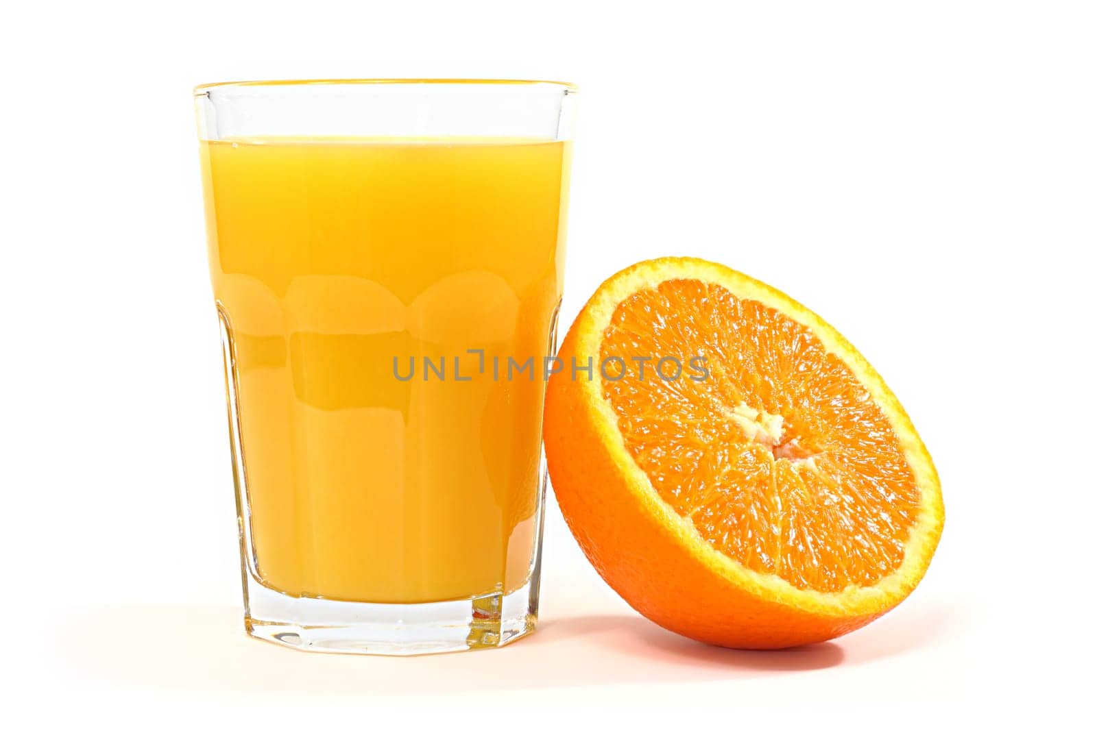 A glass of orange juice with half an orange