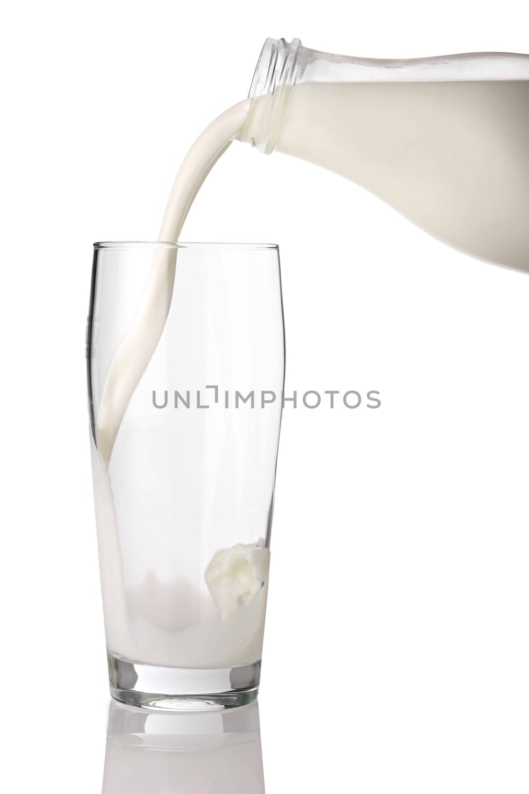 Milk from milk bottle poured into glass.