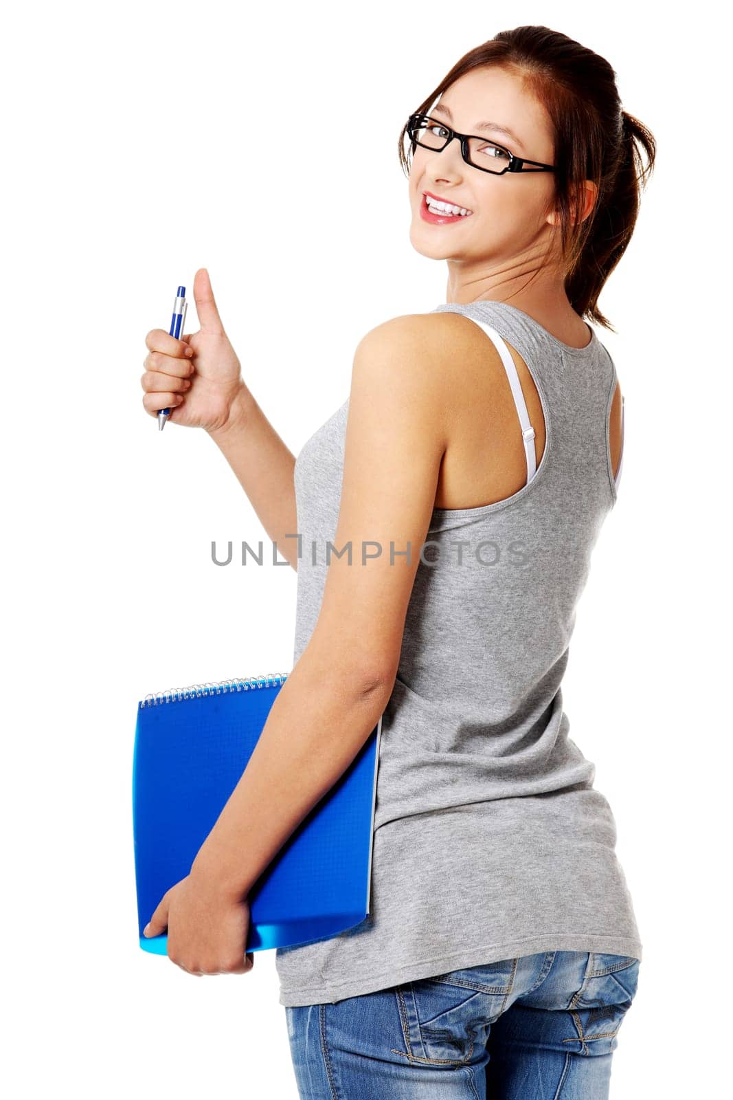 Young pretty caucasian girl standing and holding a blue notebook and a pen.