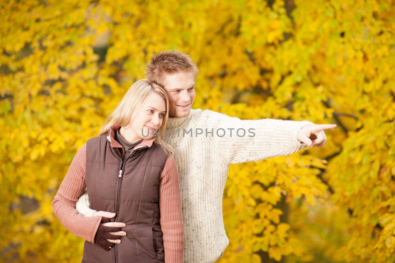 Autumn romantic couple happy together hugging in park pointing
