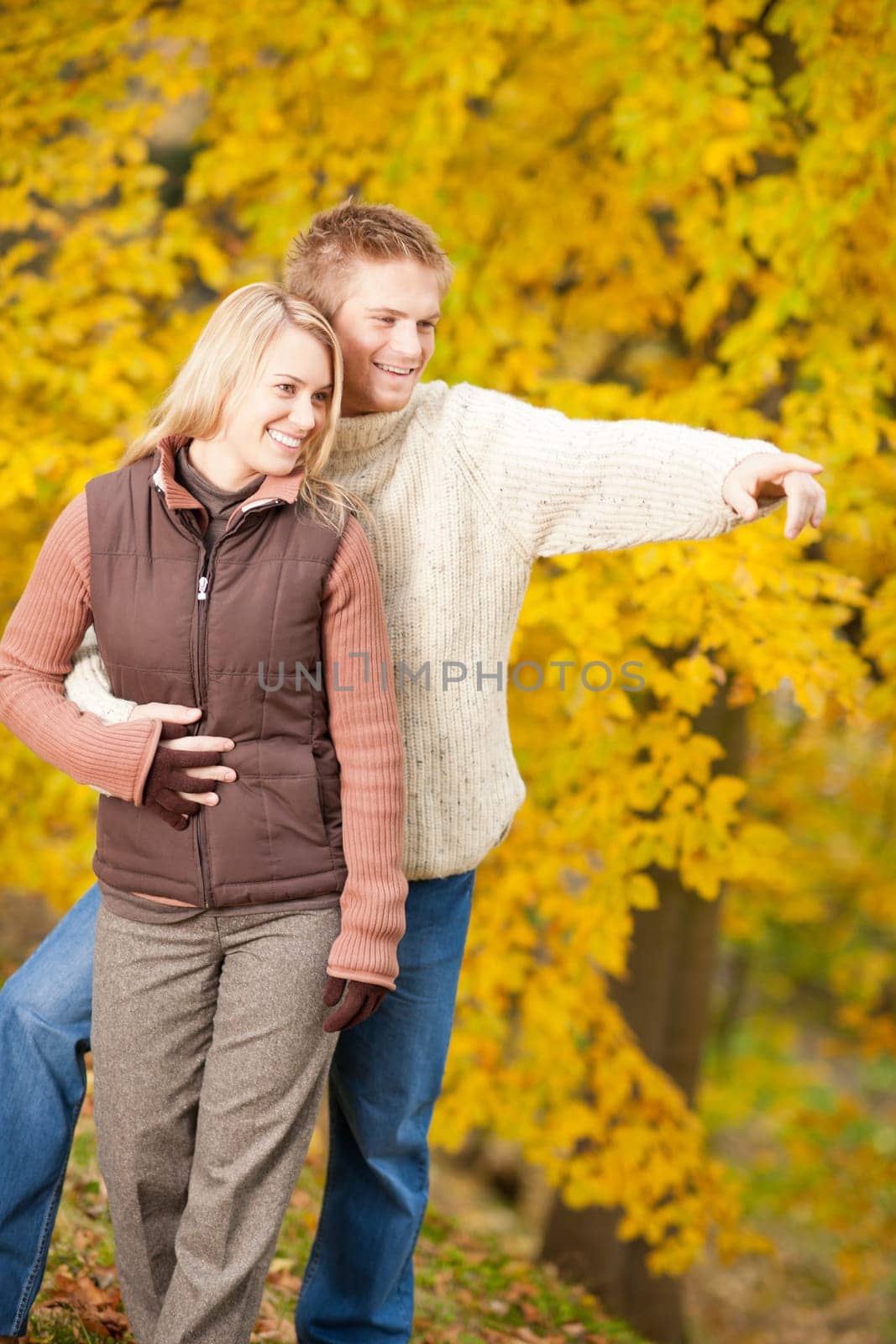 Autumn romantic couple happy together hugging in park pointing