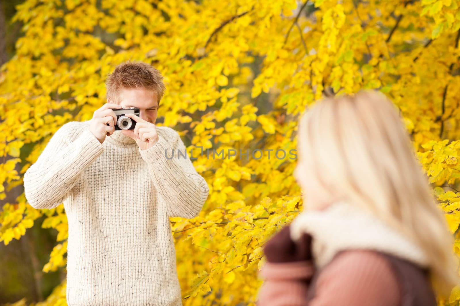 Young man make photo of posing woman profile in autumn park