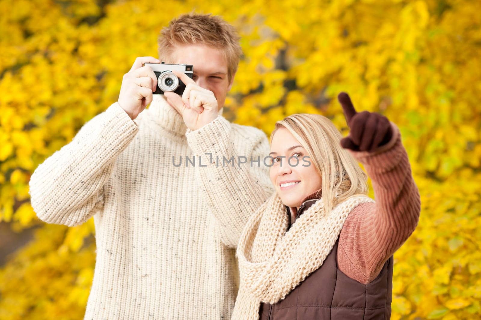 Young happy couple making photo in autumn park pointing at