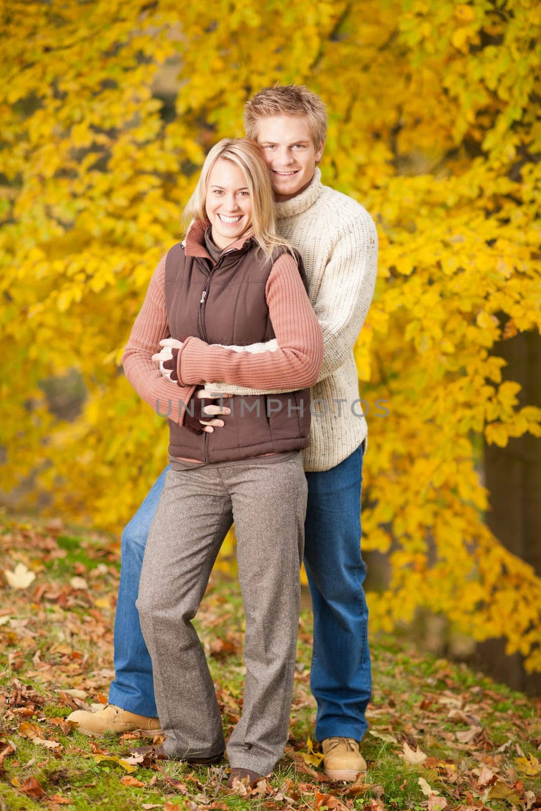 Smiling young couple in love hugging in autumn park together