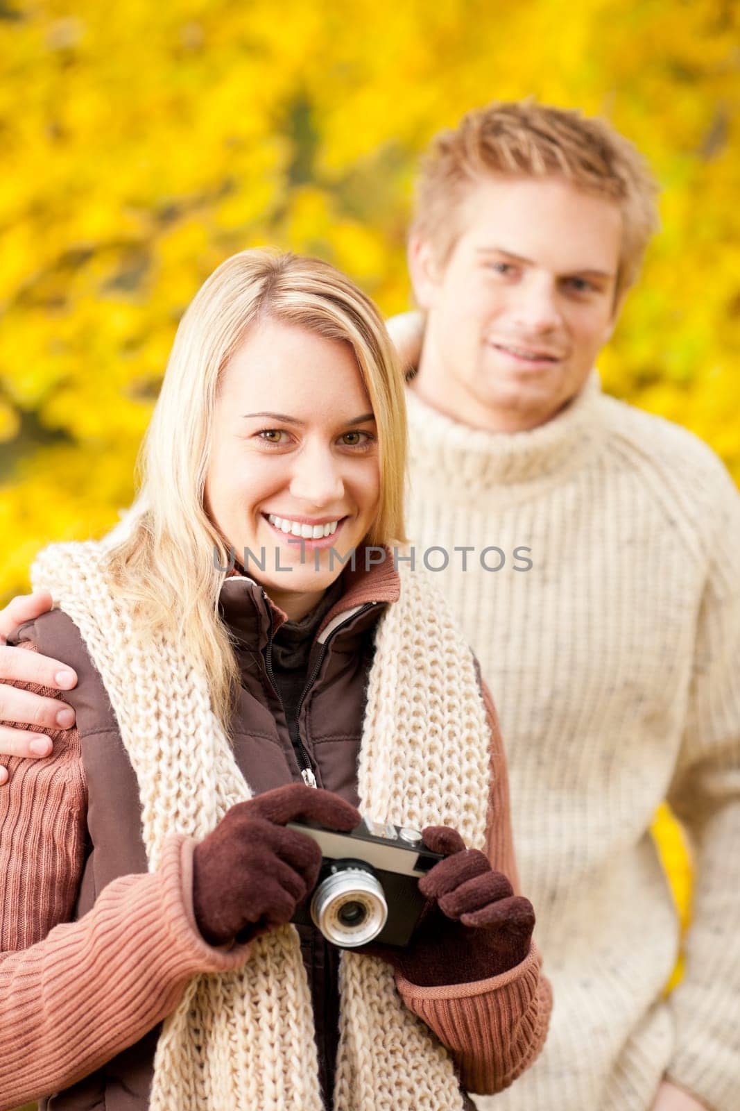Young happy couple woman making photo in autumn park