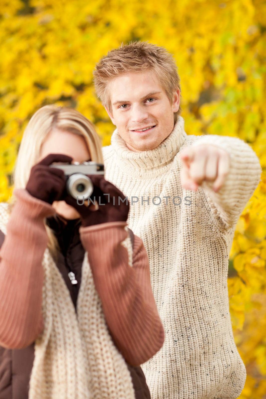 Young happy couple woman making photo in autumn park pointing