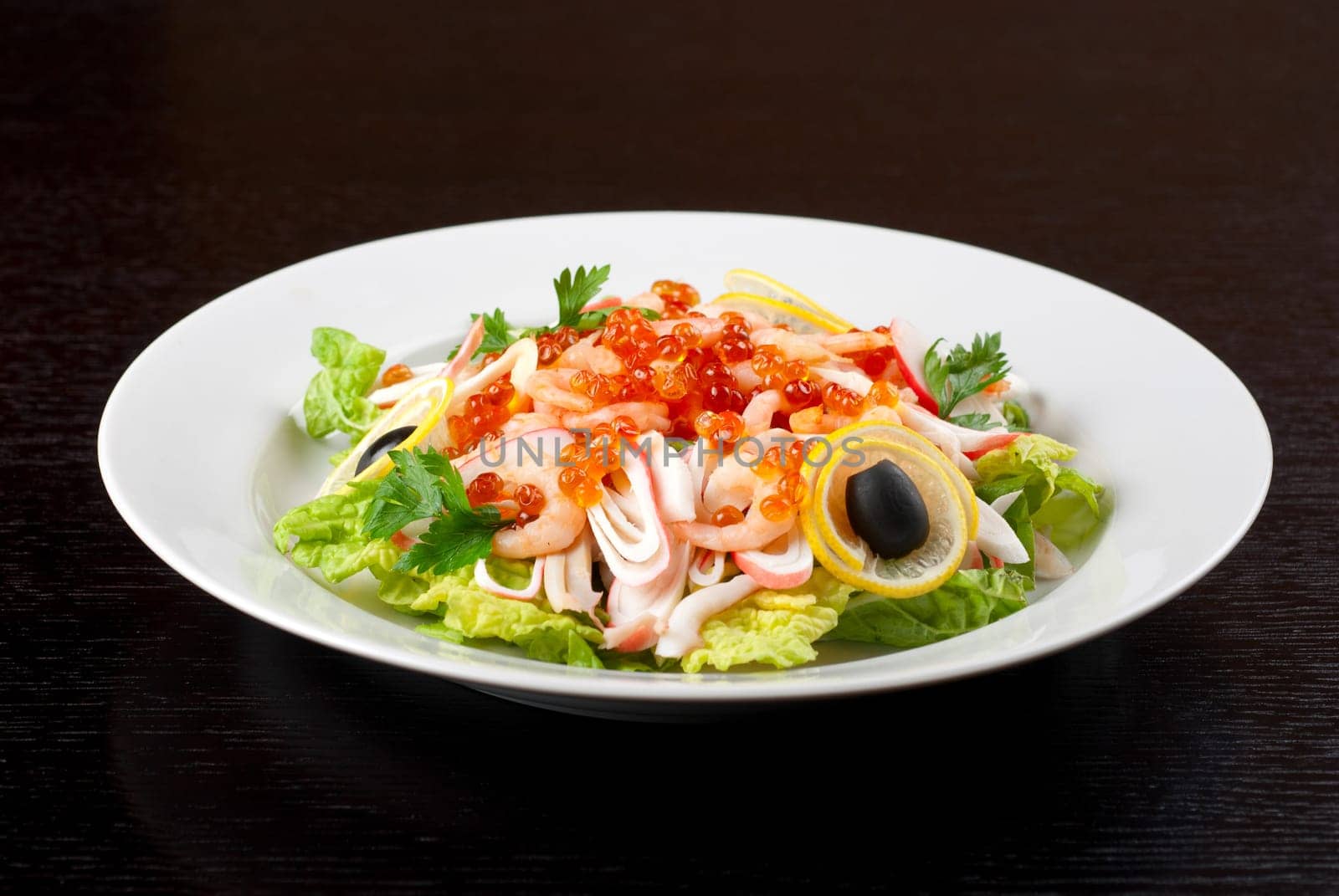 Salad with shrimps, caviar, calamaries, lettuce, lemon and olive